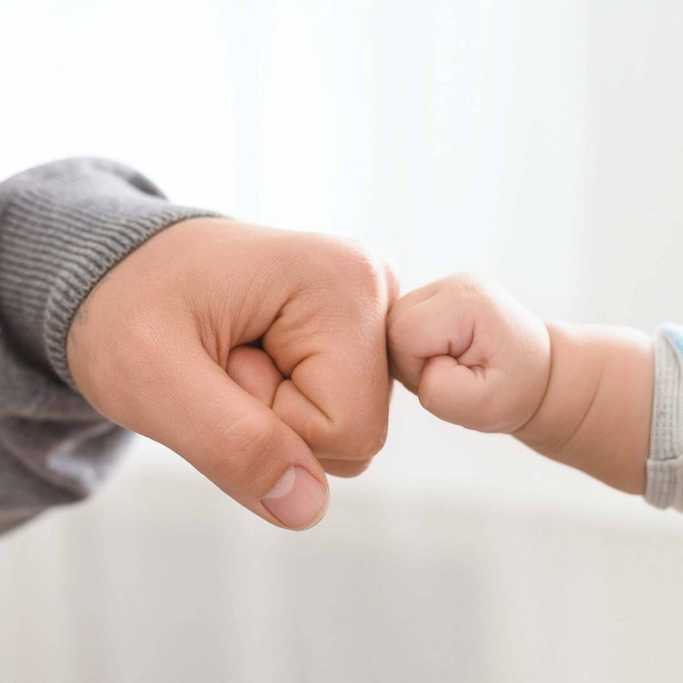 A baby&rsquo;s hand holding a wooden teething ring with pastel silicone beads